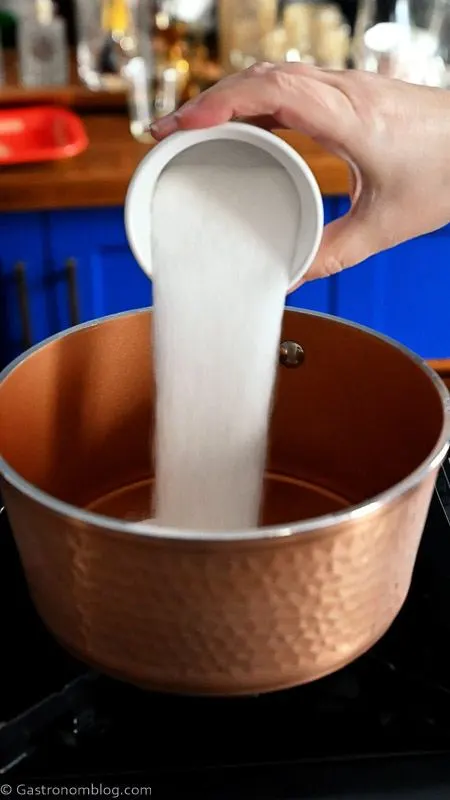 pouring sugar into a copper saucepan