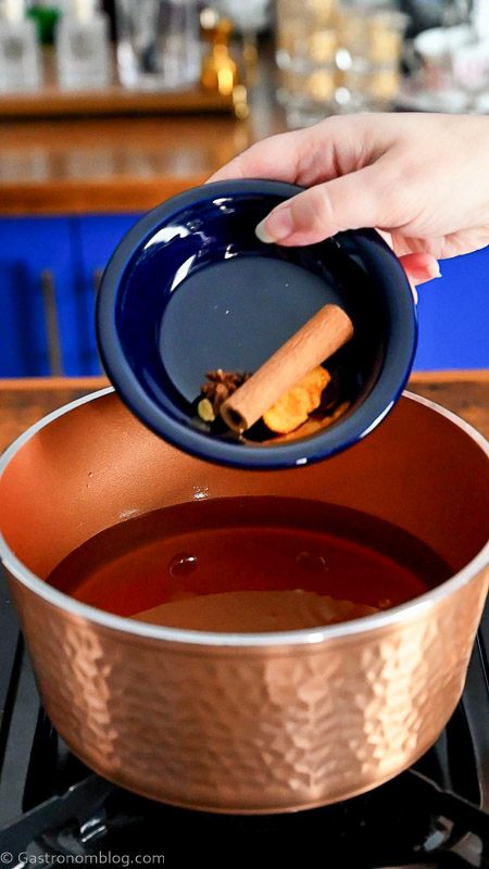 spices being poured from blue bowl into copper saucepan