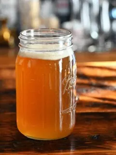 golden spiced honey syrup in a large jar on a wooden table