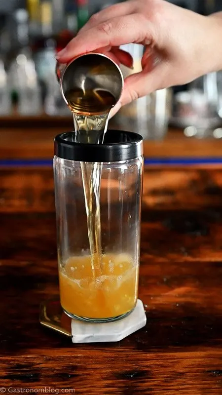 whiskey being poured into cocktail shaker