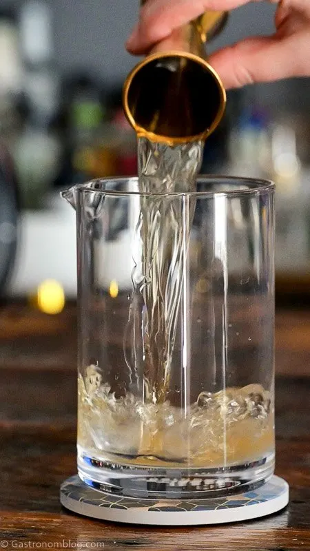 whiskey being poured into mixing glass