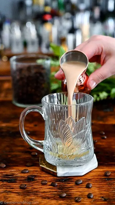 irish cream being poured from jigger into glass