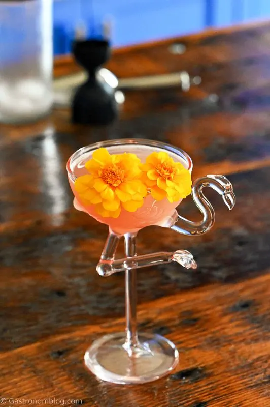 Pink Watermelon Gimlet cocktail in pink flamingo cocktail glass, yellow flowers garnish