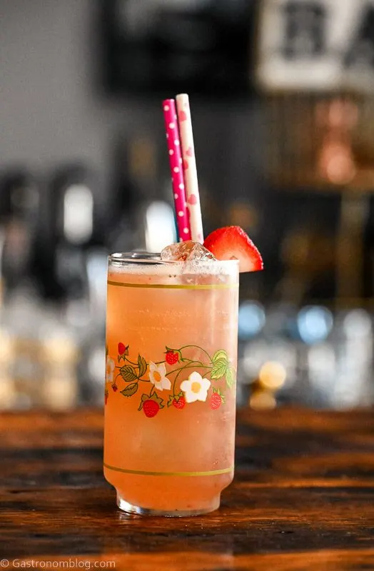 pink Strawberry Vanilla cocktail in strawberry printed vintage glass with strawberry on rim and pink straws