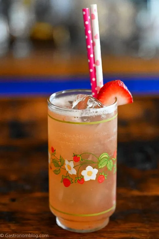 pink Strawberry Vanilla cocktail in strawberry printed vintage glass with strawberry on rim and pink straws