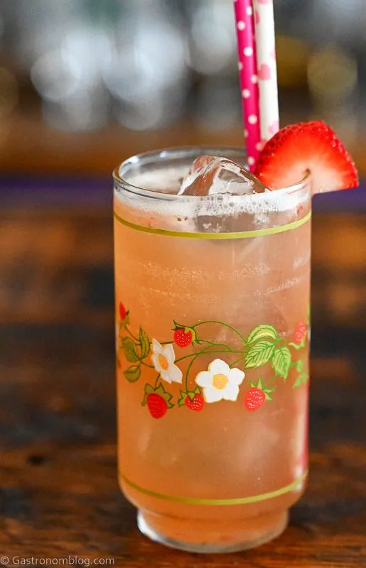 pink Strawberry Vanilla cocktail in strawberry printed vintage glass with strawberry on rim and pink straws