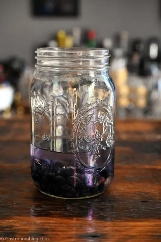 purple homemade blueberry infused vodka in mason jar on wood table