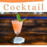 pink colored lavender syrup cocktail in a tall coupe with a basil leaf garnish on white coaster on wood table.