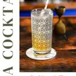 orange and white colored Earl Grey Collins cocktail in gray circle printed highball glass, on white coaster on wooden table
