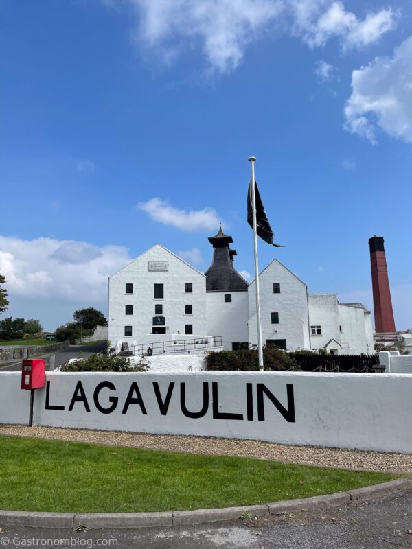 White distillery building at Lagavulin, on the isle of Islay, Scotland. Brick smokestack behind