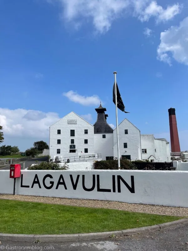 White distillery building at Lagavulin, on the isle of Islay, Scotland. Brick smokestack behind