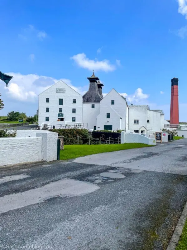 White distillery building at Lagavulin, on the isle of Islay, Scotland. Brick smokestack behind