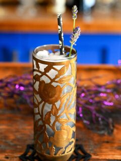 Midnight Margaritas in Metal chased floral tumblers with skull straw, lavender garnishes on wooden table