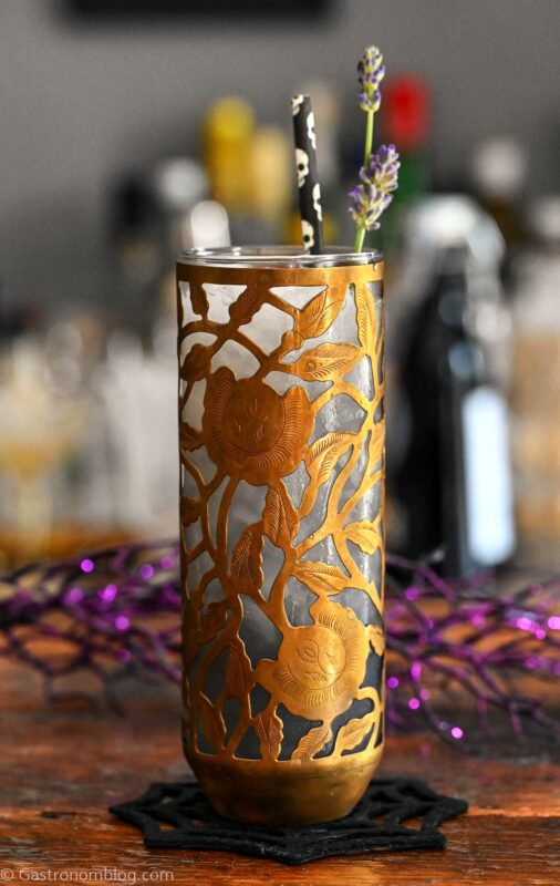Midnight Margaritas in Metal chased floral tumblers with skull straw, lavender garnishes on wooden table