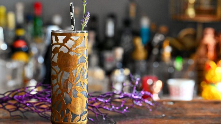 Midnight Margaritas in Metal chased floral tumblers with skull straw, lavender garnishes on wooden table