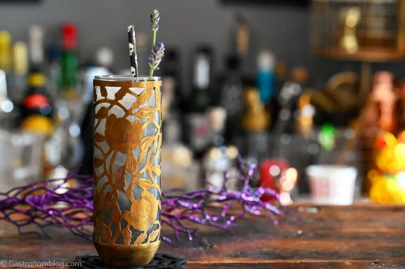 Midnight Margaritas in Metal chased floral tumblers with skull straw, lavender garnishes on wooden table