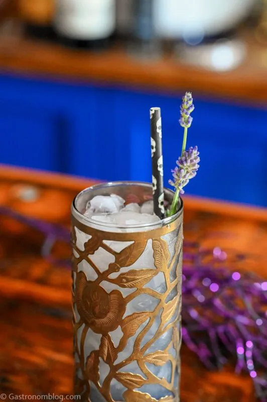 Midnight Margaritas in Metal chased floral tumblers with skull straw, lavender garnishes on wooden table