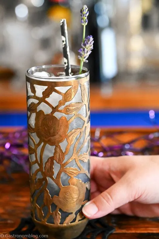 Midnight Margaritas in Metal chased floral tumblers with skull straw, lavender garnishes on wooden table