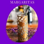 Midnight Margaritas in Metal chased floral tumblers with skull straw, lavender garnishes on wooden table