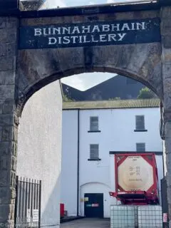 view through arch between white buildings during Bunnahabhain Distillery Tour