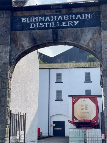 view through arch between white buildings during Bunnahabhain Distillery Tour