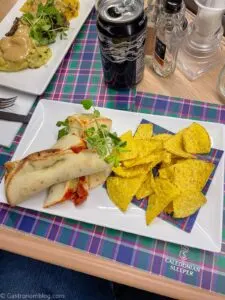 rollup tortilla and chips on white plate on tartan placemat on Caledonian Sleeper Train
