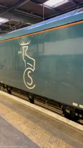 outside of green Caledonian Sleeper Train with stag logo