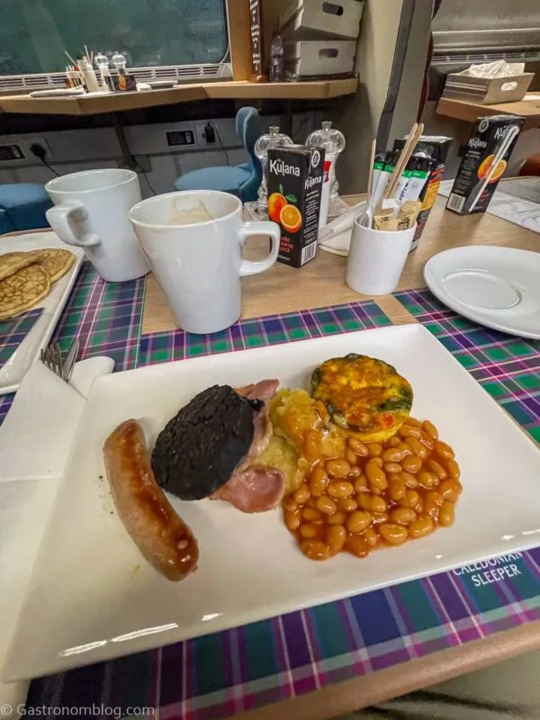 Scottish breakfast on white plate and tartan placemat in club car on Caledonian Sleeper Train