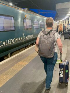 green Caledonian Sleeper Train in Eustan Train Station in London, lady walking with luggage