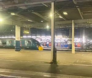 Green Caledonian Sleeper Train on other track at train station