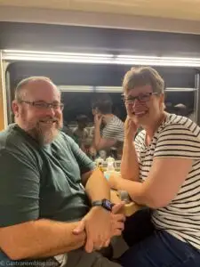 man and woman turned for a picture on stools in club car at Caledonian Sleeper Train