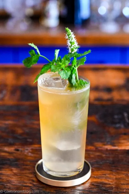tan Earl Grey Gin Cocktail in tumbler with mint sprig garnish on wooden table