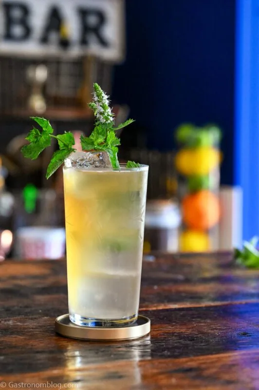 tan Earl Grey Gin Cocktail in tumbler with mint sprig garnish on wooden table
