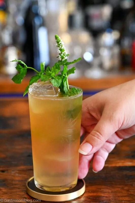tan Earl Grey Gin Cocktail in tumbler with mint sprig garnish on wooden table