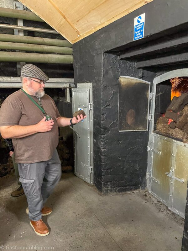 man throwing peat into fire at Laphroaig Distillery