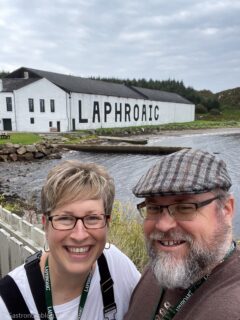 man and woman smiling at camera in front of white building at Laphroaig Distillery