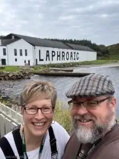man and woman smiling at camera in front of white building at Laphroaig Distillery