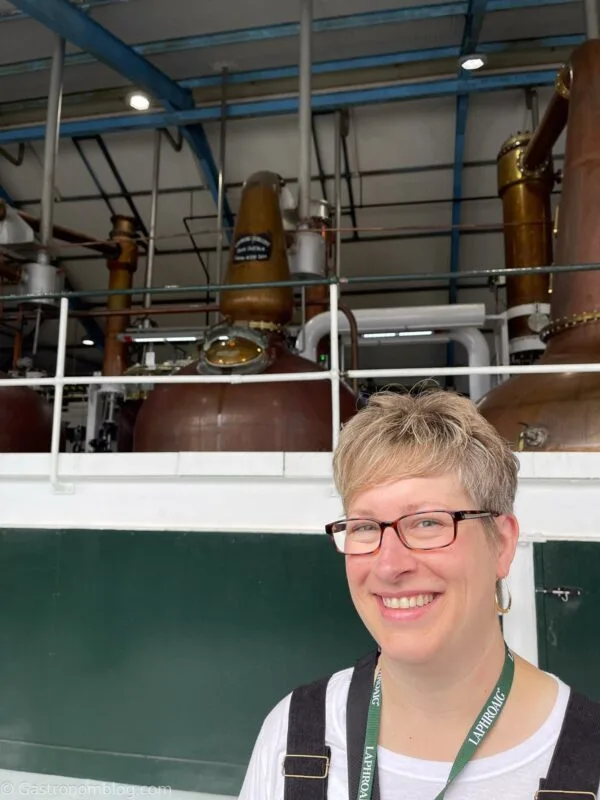 woman in front over stills at Laphroaig Distillery