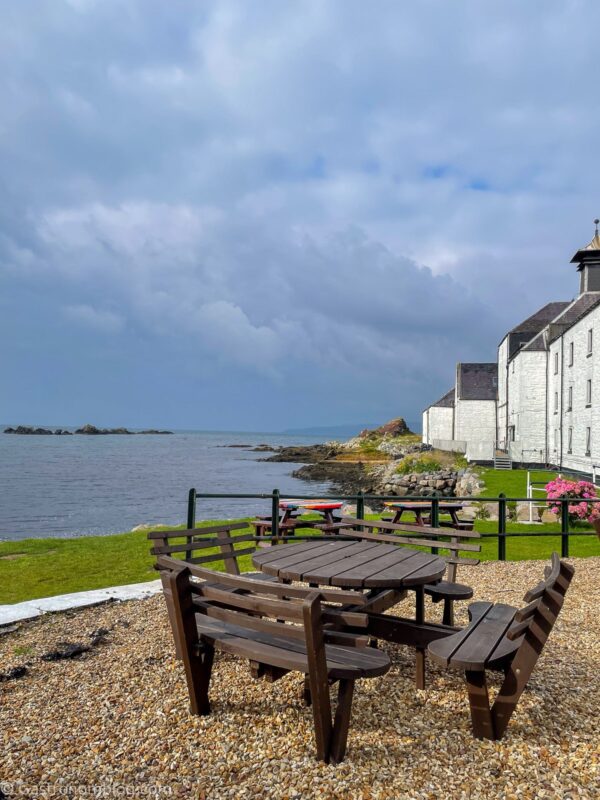 picnic tables in front of white building at Laphroaig Distillery