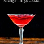 red Stranger Things Drink with dried dragonfruit chip garnish in cocktail coupe on wooden table with black background